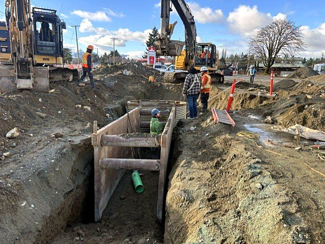 Trench box with green PVC pipe leading to a CSP manhole