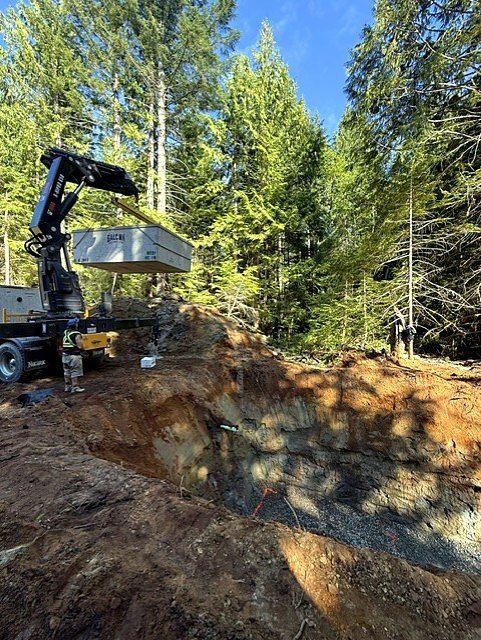 Crane truck lowering a precast concrete structure into an excavation
