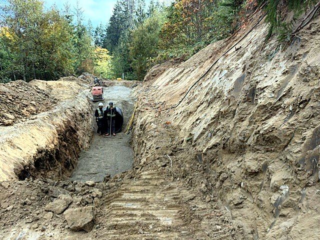 Crew installing drainage pipe in a deep cut slope
