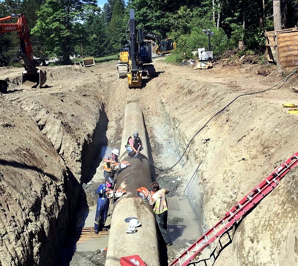 Step 2, cut: crew cutting the old pipe into sections in the trench