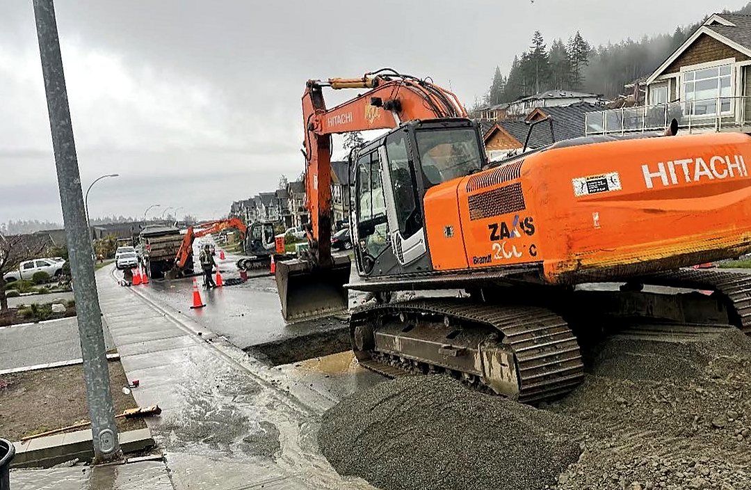 Hitachi excavator working on a city street with traffic control